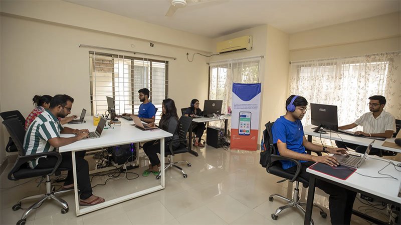Young Bangladeshi technology entrepreneur working on a laptop in a small startup workspace