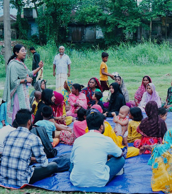 Bangladeshi community members and a microfinance field officer having a respectful conversation outdoors